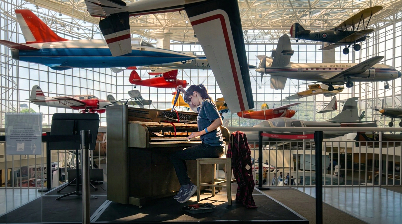 Jordan A. Cook working on a Steinway Victory Vertical at the Seattle Museum of Flight, historic aircraft suspended overhead
